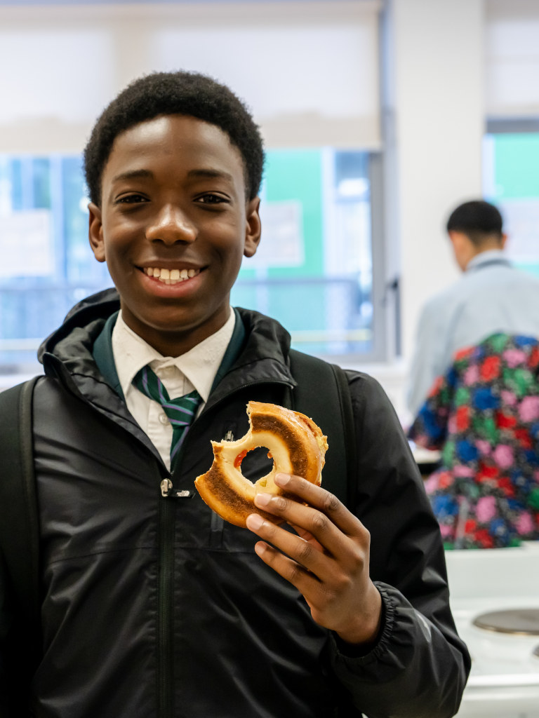 boy in kitchen with bagel smiling