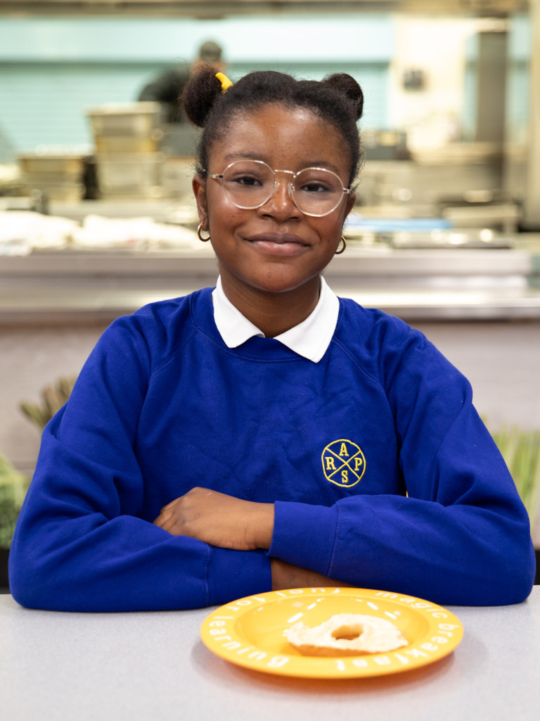 smiling girl in school jumper with egg breakfast